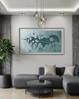 A modern living room with a gray sectional sofa, a round glass coffee table, a potted plant, and a large framed abstract art print on the wall above the sofa.