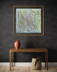 A framed abstract art print featuring colorful scribbled lines on a light blue background, hung on a dark textured wall above a wooden console table with a terracotta vase and a woven basket.
