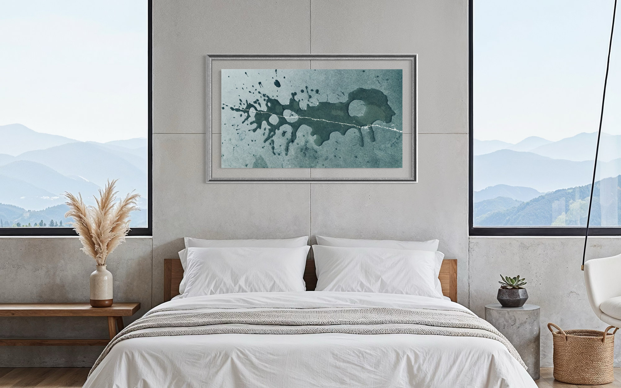 A framed abstract wall art print with a teal and black paint splatter design hangs above a neatly made bed in a modern, minimalist bedroom with concrete walls and large windows showing a mountain view.