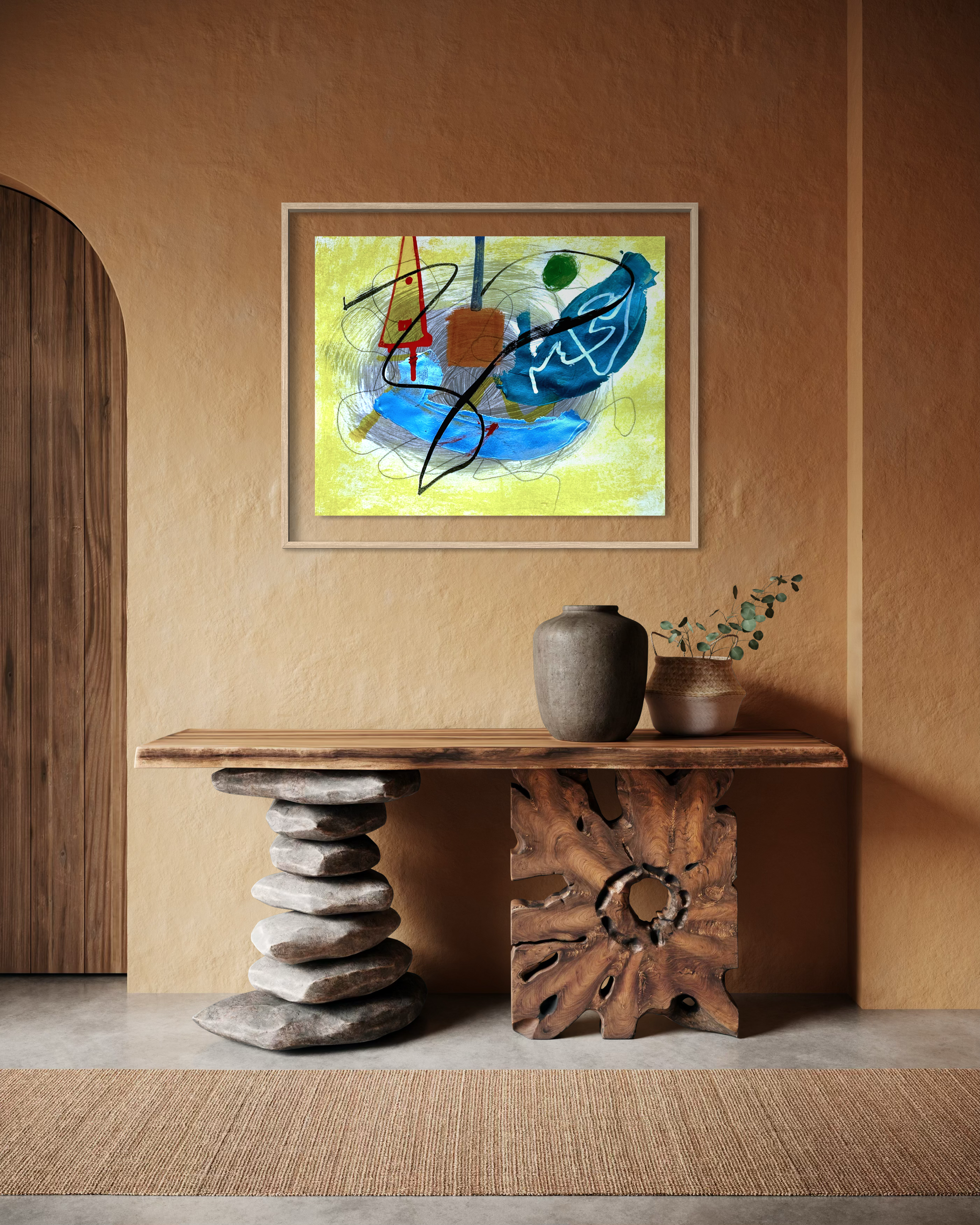 An abstract framed painting with blue, yellow, green, and red brushstrokes hangs on a warm brown textured wall above a rustic wooden console table with stone and wood bases.