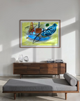 A framed abstract painting with blue, yellow, orange, and black brushstrokes hangs on a white wall in a modern dining room with a gray settee, chairs set up around a table with open glass doors and abundant light