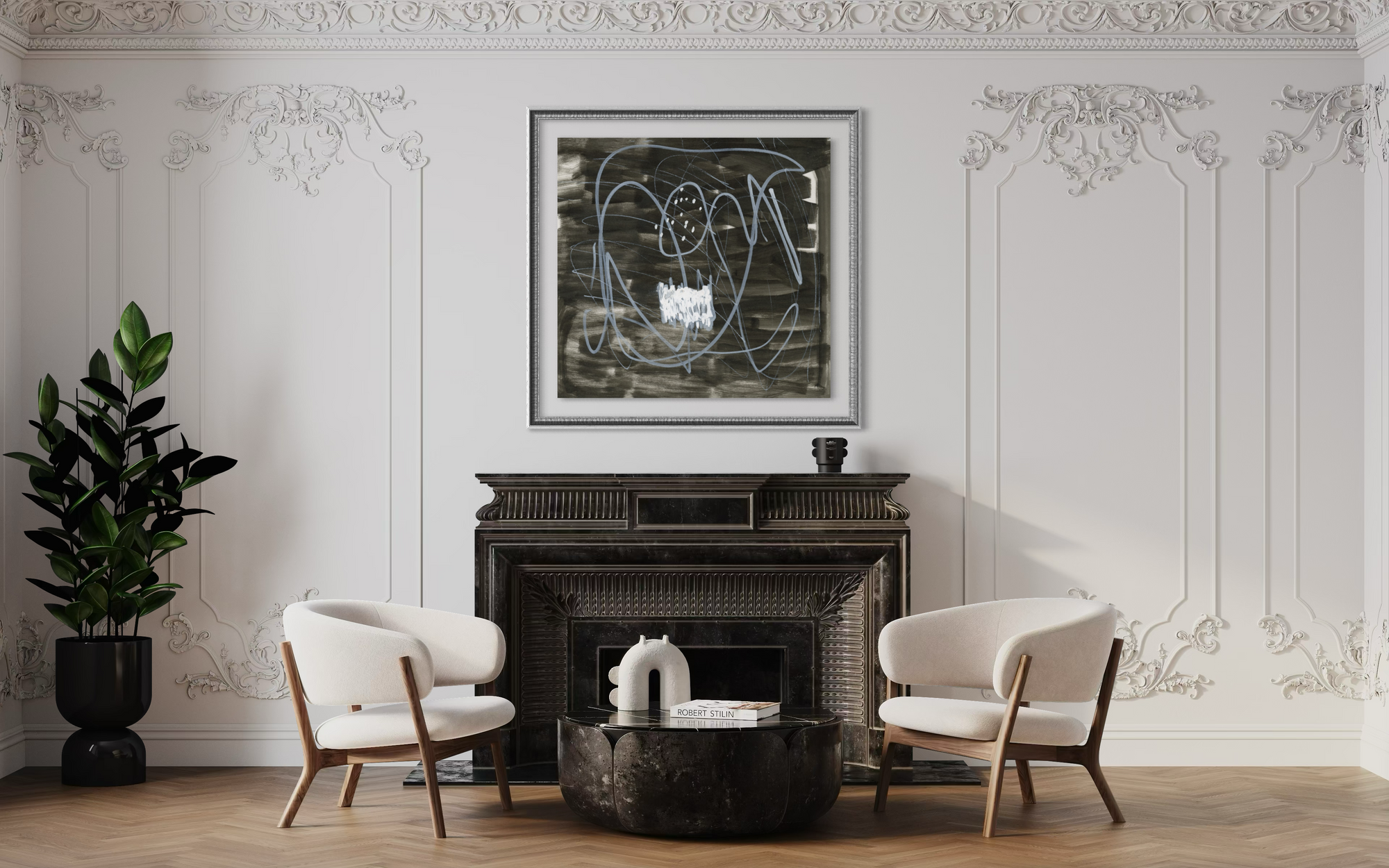 A framed abstract black and white artwork hangs above a dark fireplace in a styled living room with two white armchairs, a round dark coffee table, and a potted plant against ornate white wall molding.