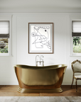 Brass bathtub with a chair in a well lit room and an abstract piece of arton wall