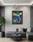 A colorful abstract geometric wall art print in a black frame hangs above a modern gray sectional sofa in a contemporary living room with concrete walls, a city view, and a potted plant.