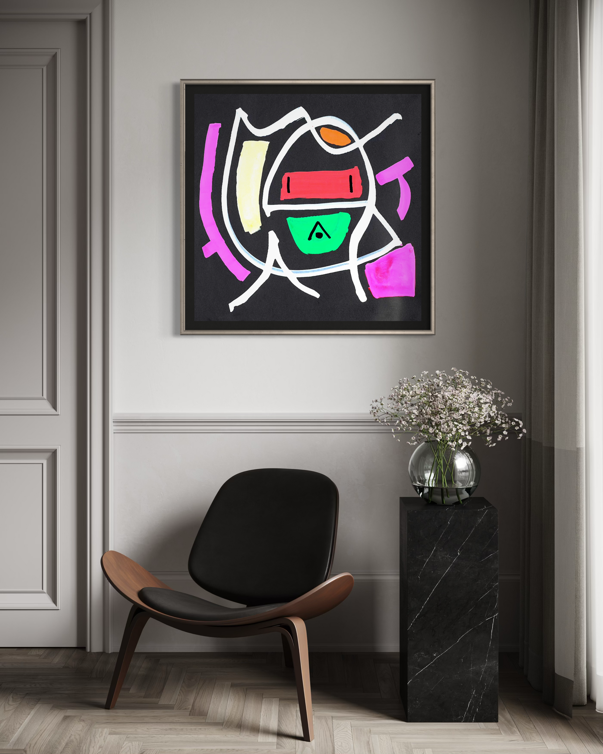 A framed abstract geometric wall art print hangs on a light gray wall above a black and wood lounge chair, next to a black marble side table with a vase of baby's breath.