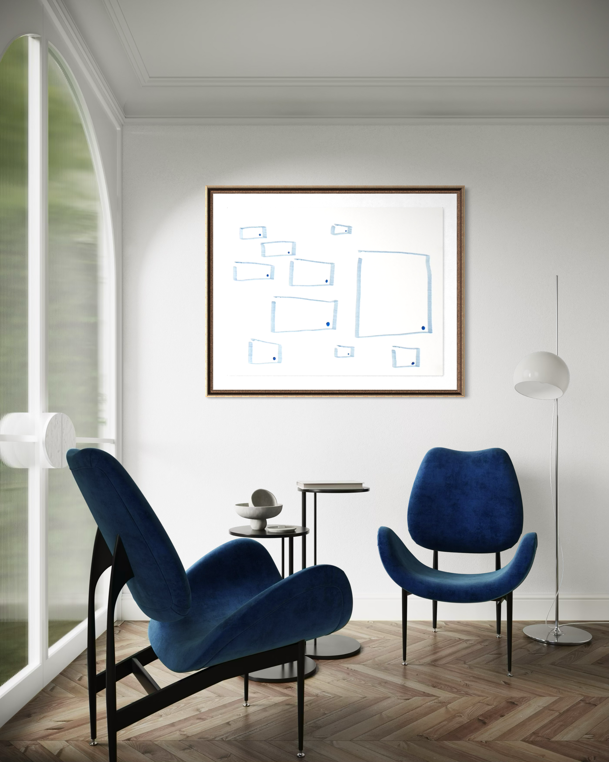 A framed minimalist art print with blue line drawings on a white background, hanging on a white wall in a modern living room setting with two blue armchairs and a wooden floor.