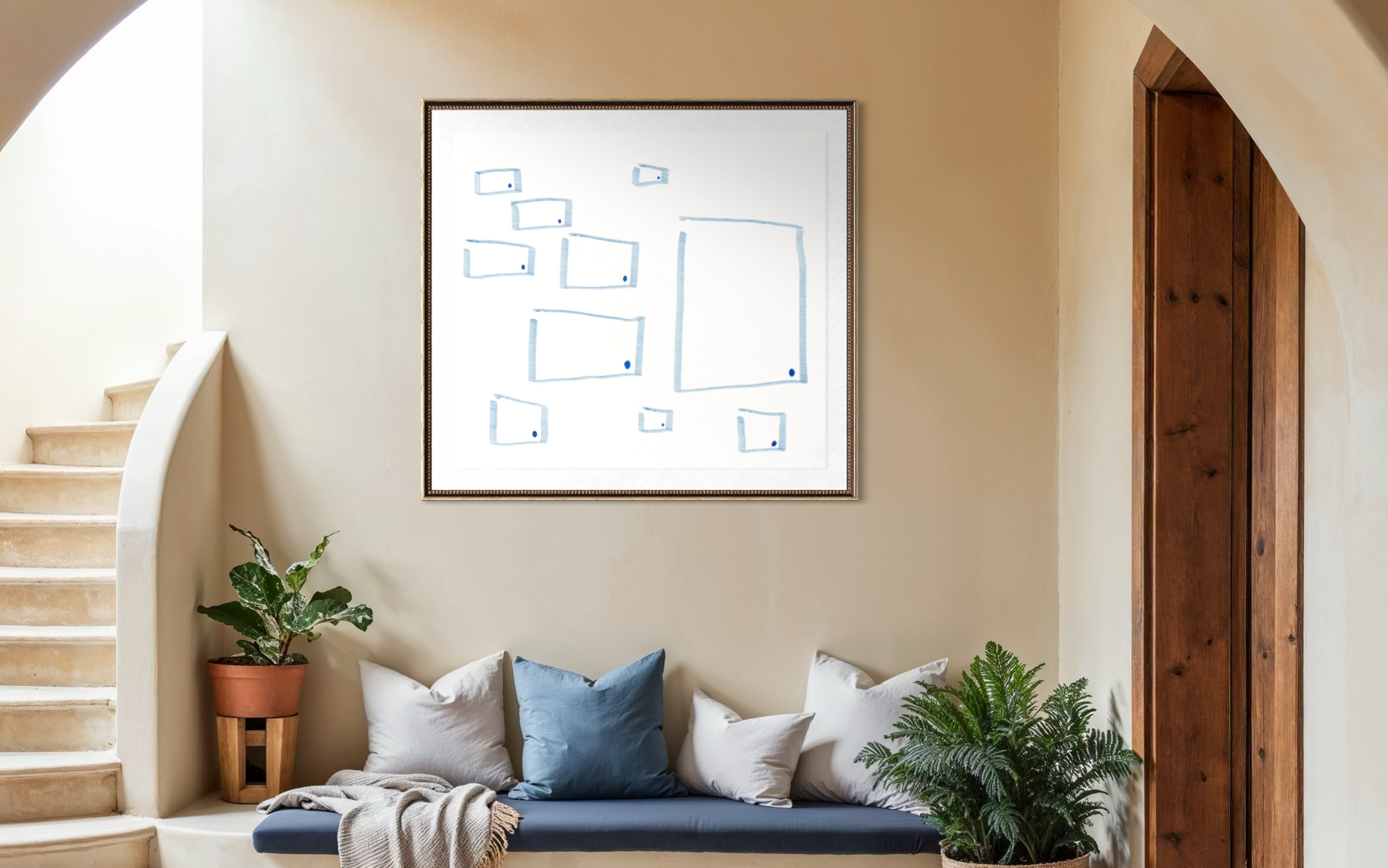 A framed minimalist art print with blue geometric line drawings on a white background, hanging on a beige wall above a blue bench with pillows in a styled interior setting.