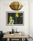 A framed abstract painting hangs on a white paneled wall in a dining room setting. The painting features bold brushstrokes in black, green, yellow, and blue.